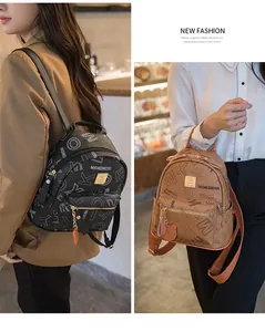 Detail of elegant patterned backpacks in black and brown with metal logo and charm