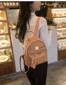 Detail of a brown PU leather mini backpack with monogram pattern and gold metal logo