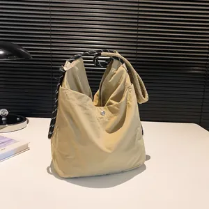 Minimalist beige nylon crossbody bag featuring a stylish black and white woven strap