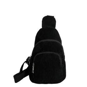Detail of black corduroy chest bag featuring multiple zippered pockets and adjustable strap