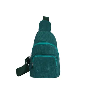Detail of dark green corduroy chest bag featuring multi-pocket zipper design and strap