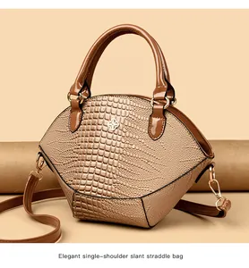 Dettaglio dell'elegante trama a coccodrillo beige e logo metallico sulla borsa a guscio