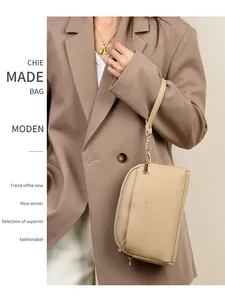 Dettaglio borsa in pelle beige con doppia cerniera e finiture dorate su una modella