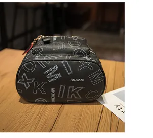 Close-up of black lychee grain leather backpack with white lettering and red heart charm