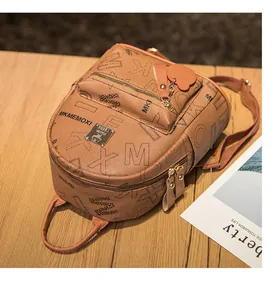 Detailed close-up of brown PU mini backpack with letter prints on a wooden surface