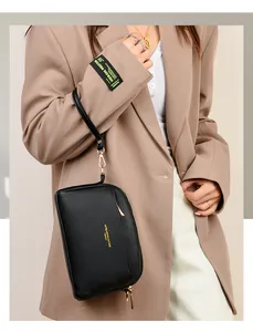 Dettaglio borsa a polso in pelle martellata nera con zip dorata e logo moda