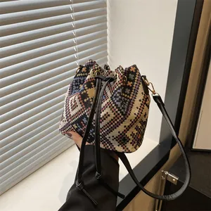 Detail of woven bucket bag with geometric patterns, drawstring closure and metal hooks