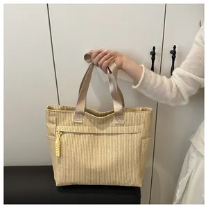 Detail van beige corduroy draagtas met geel knoopdetail en satijnen handgrepen