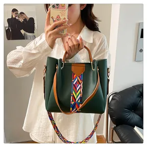 Dettaglio di borsa tote verde scuro con manici marroni e tracolla geometrica colorata