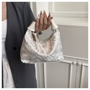 Detail of silver embroidered handbag with geometric patterns and beaded tassel charm