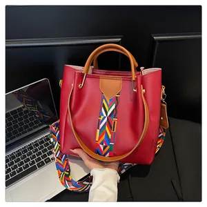 Dettaglio della borsa tote in pelle rossa con ampia tracolla in tessuto etnico colorato