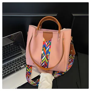 Dettaglio della borsa rosa chiaro con tracolla colorata stile etnico e manici marroni