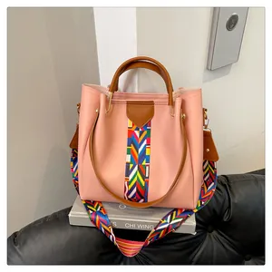 Dettaglio borsa rosa con tracolla etnica intrecciata colorata su un divano