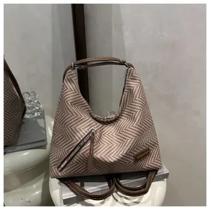 Close-up of herringbone fabric texture and leather label on this versatile shoulder bag