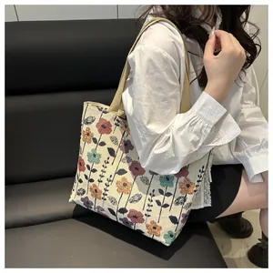 Detail of floral canvas tote bag with colorful embroidery and khaki woven straps