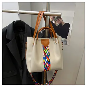 Dettaglio borsa tote beige con nastro geometrico colorato e manici in pelle marrone
