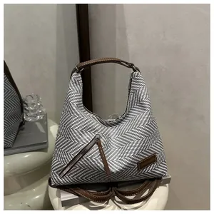 Detail of hobo bag with black and white woven texture and brown leather strap