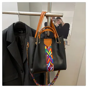 Dettaglio della borsa tote nera con tracolla etnica e manici in similpelle marrone