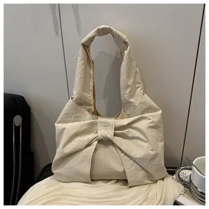 Detailed view of cream hobo bag with large decorative bow and soft wrinkled texture