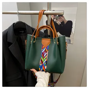 Dettaglio della borsa in pelle opaca verde scuro con tracolla colorata e finiture dorate