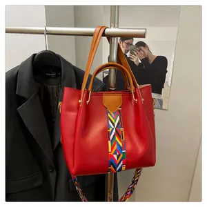 Dettaglio della borsa tote in pelle rossa con tracolla etnica intrecciata e manici superiori