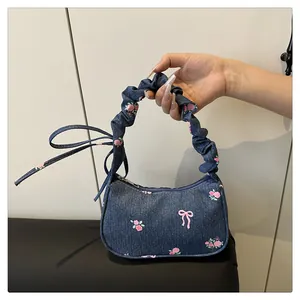 Close-up of denim bow print handbag featuring gathered handle and ribbon detail