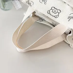 Detailansicht der weißen Cord-Tragetasche mit süßem schwarzen Bären und Smile-Schriftzug