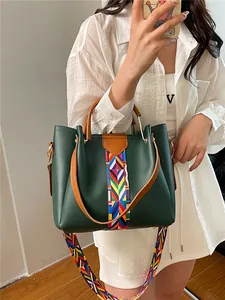 Borsa tote verde scuro con tracolla etnica tessuta e doppi manici marroni in un selfie