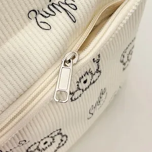 Nahaufnahme von cremefarbenem Cordstoff mit Smile-Schriftzug und Metallreißverschluss