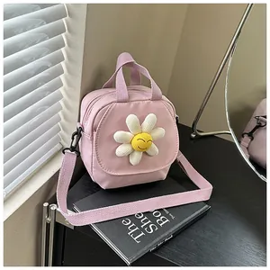 Detailed shot of a pink canvas crossbody bag with a white 3D daisy flower charm and strap