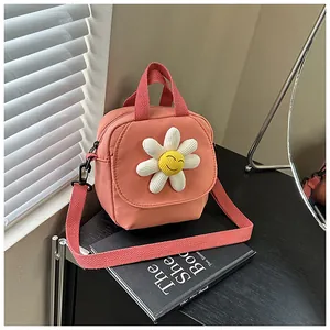 Detailed view of pink canvas crossbody bag with 3D sunflower smile charm on desk