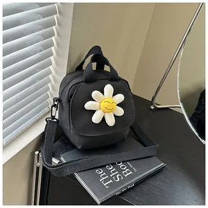 Detail of black canvas bag with a 3D daisy flower charm and adjustable shoulder strap