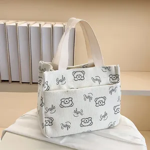 Detail der cremefarbenen Cord-Tasche mit Bärenmuster und Smile-Schriftzug
