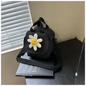 Close-up of black canvas crossbody bag featuring a white daisy with yellow smiley face