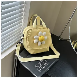 Detail of yellow canvas crossbody bag featuring a 3D sunflower smile and metal hardware