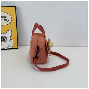 Detail of coral pink crossbody canvas bag with daisy flower and thick strap on white desk