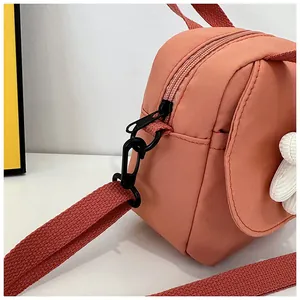 Detail of pink nylon crossbody bag showing black plastic zipper and swivel strap buckle