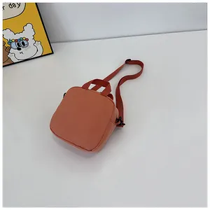 Detailed overhead view of a bright orange square canvas crossbody bag with shoulder strap