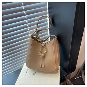Detailed shot of camel bucket bag with contrast stitching and gold ring closure