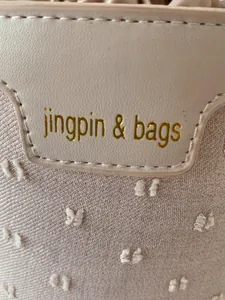 Detailed close-up of pink leather logo tag and textured fabric on the bucket bag