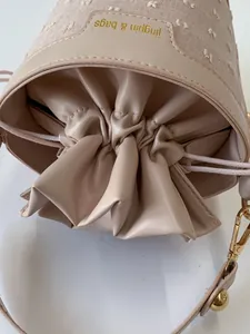 Close-up of beige drawstring bucket bag with floral embroidery and gold hardware