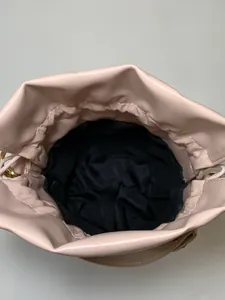 Top view of spacious interior of a beige bucket bag with black lining and drawstring closure
