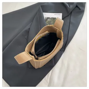 Detail view of khaki handbag featuring black fabric lining and functional inner zipper pocket