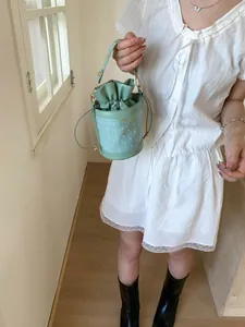 Chic mint green mini bucket bag with drawstring closure and textured patchwork style