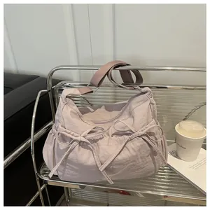 Close-up of lilac nylon shoulder bag featuring decorative drawstrings and side pockets