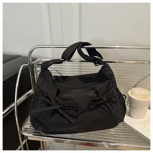 Detail of black nylon shoulder bag with bow accents and adjustable strap on a metal cart