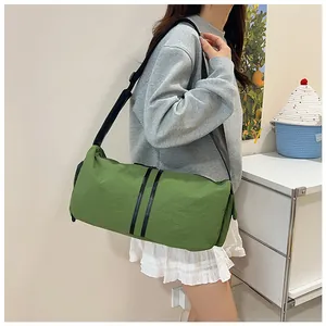 Detalle del bolso bandolera cilíndrico verde de nailon con rayas negras y correa ancha