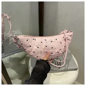 Detail of pink croissant bag with black bow patterns and knotted rope strap