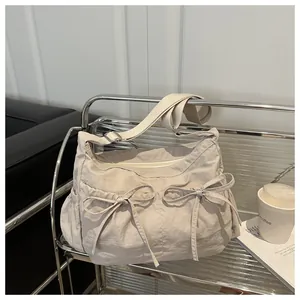Detail of off-white pleated nylon bag featuring sweet bow drawstrings and side pockets