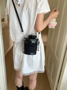 Chic black bucket bag with drawstring closure and contrasting polka dot fabric detail